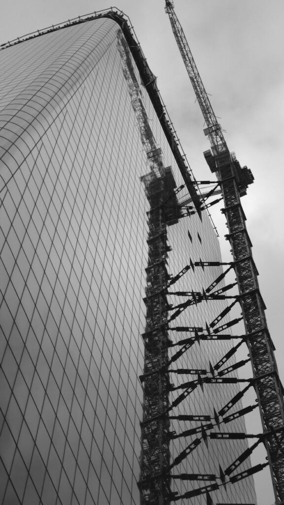 pexels-photo-1702140 Low angle view of a skyscraper under construction with cranes, captured in monochrome.
